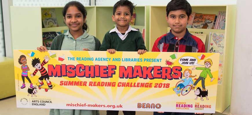three children holding banner for mischief makers summer reading challenge 2018